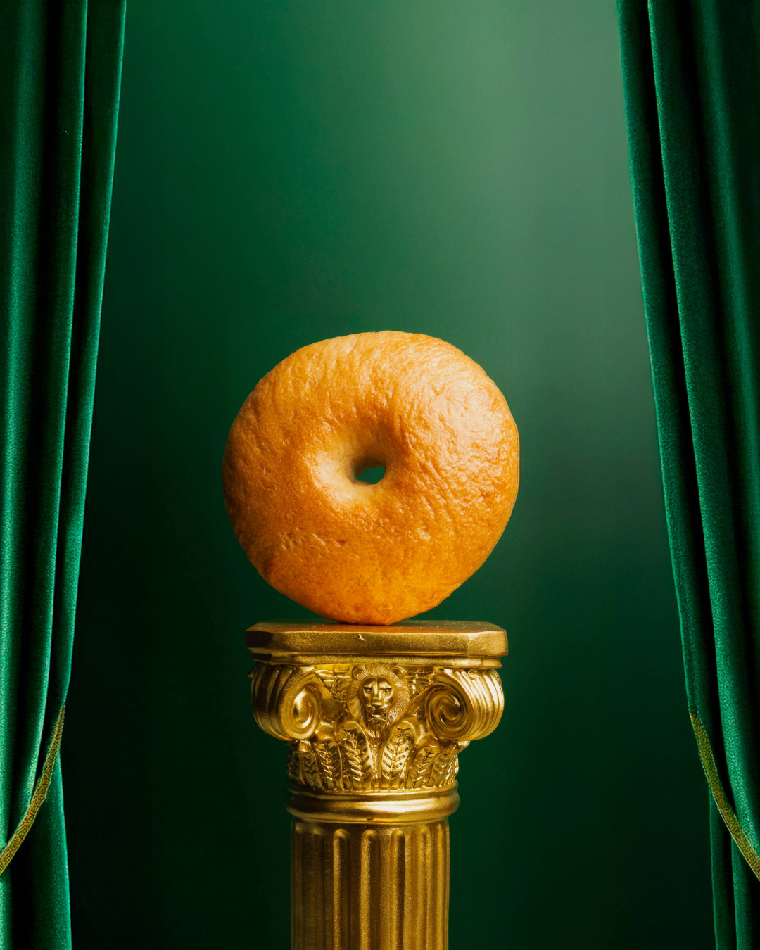 bagel on gold podium with green background